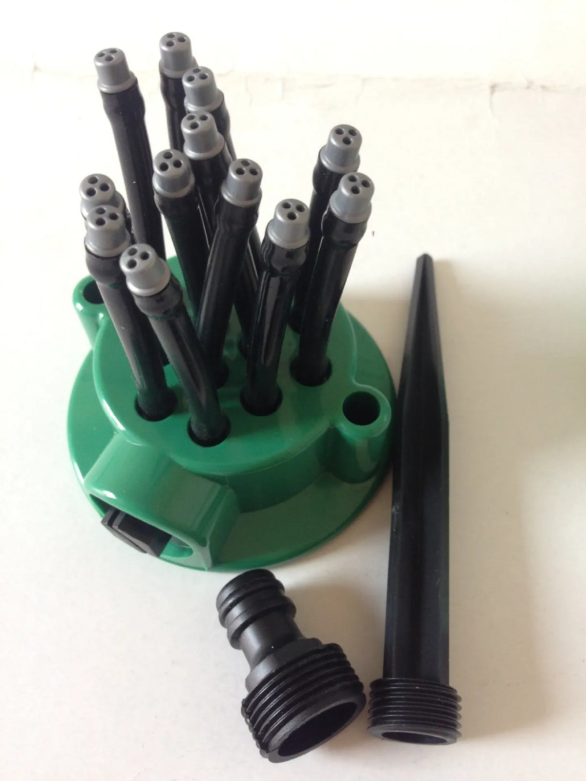 Green adjustable lawn sprinkler with bendable spray arms on a 9cm circular base.