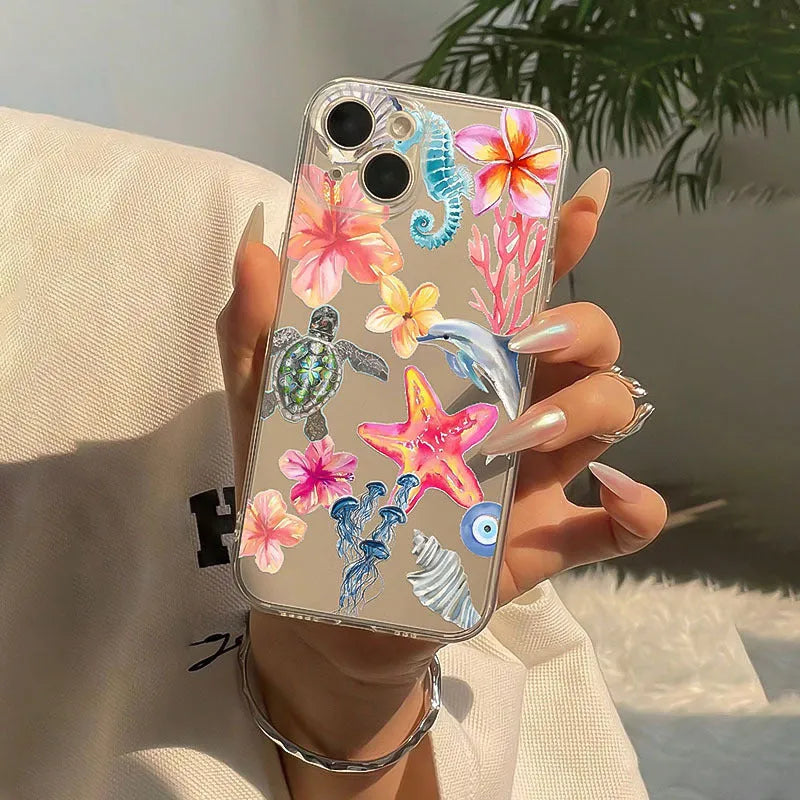 Clear transparent iPhone case with printed blue dolphin, green turtle, shell, and leaf designs.