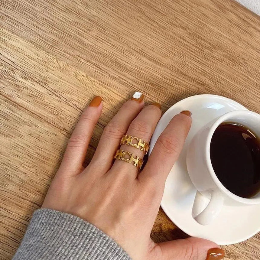 Gold titanium steel hollowed cut letter ring with geometric design on white background