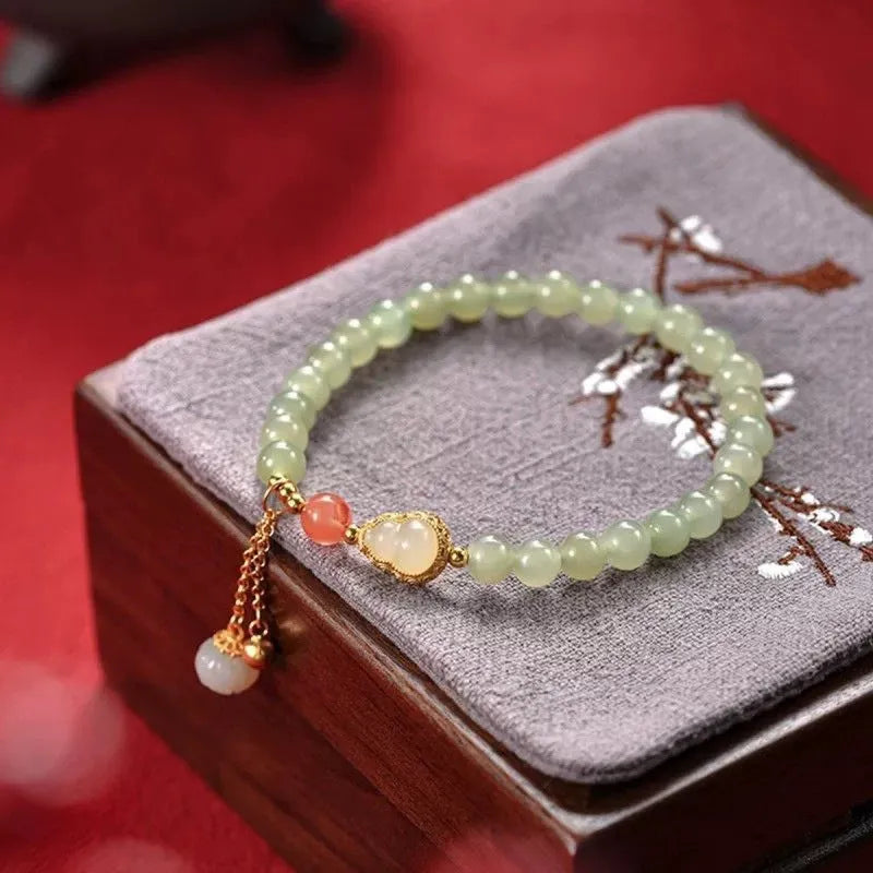Women's jade bracelet with a 6mm gold-plated gourd charm and engraved fu character.