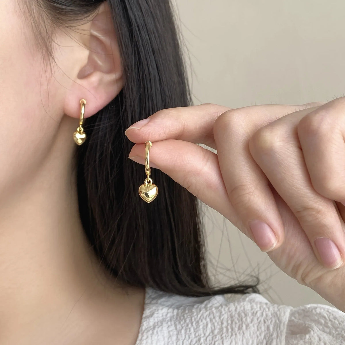 Gold copper C-shaped heart pendant earrings on white background