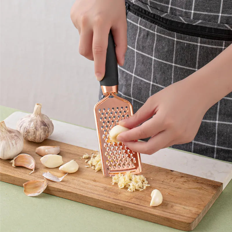 Seven-piece stainless steel kitchen tool set with copper plating on a matching storage rack.