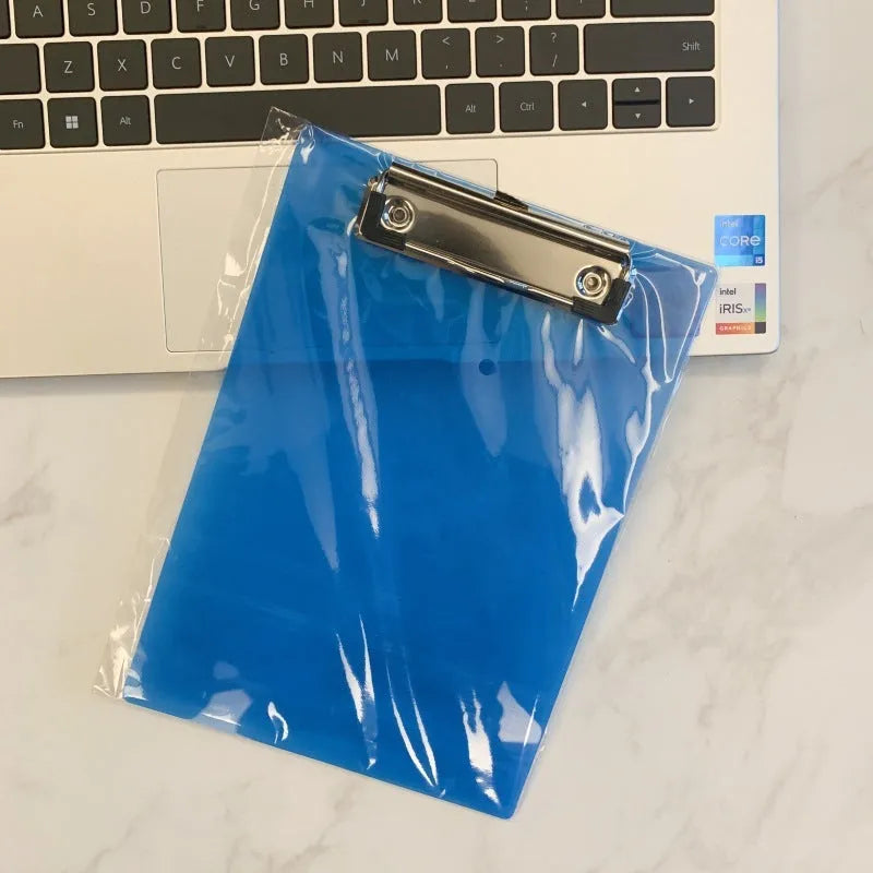 Transparent A4 clipboard with metal clip, shown in blue colour on a wooden desk.