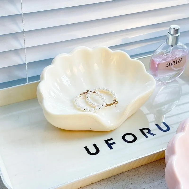 White shell-shaped plastic soap dish with drainage holes on a bathroom surface