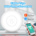 Compact white Zigbee wireless water flood sensor for smart home on a wooden surface.