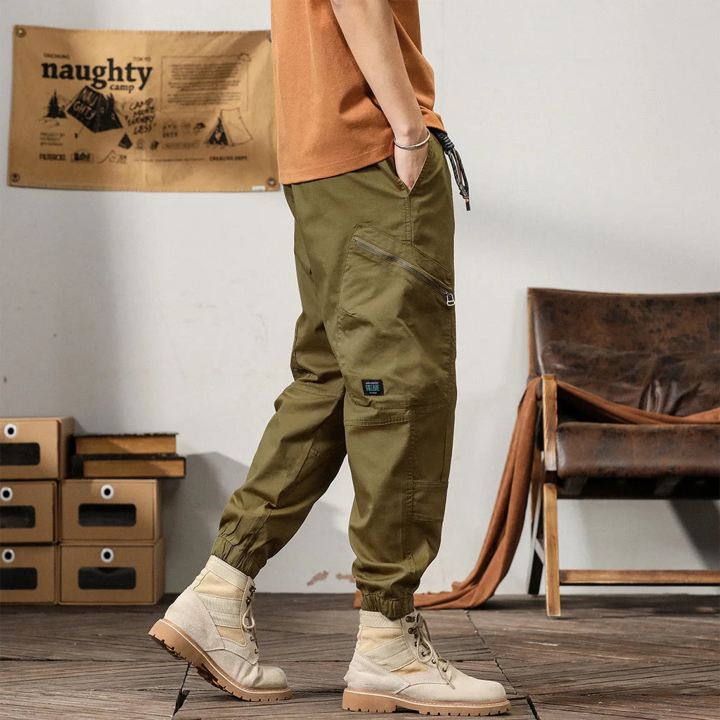 Men's khaki cotton harem pants with tapered ankle cuffs and a loose fit, shown laid flat.
