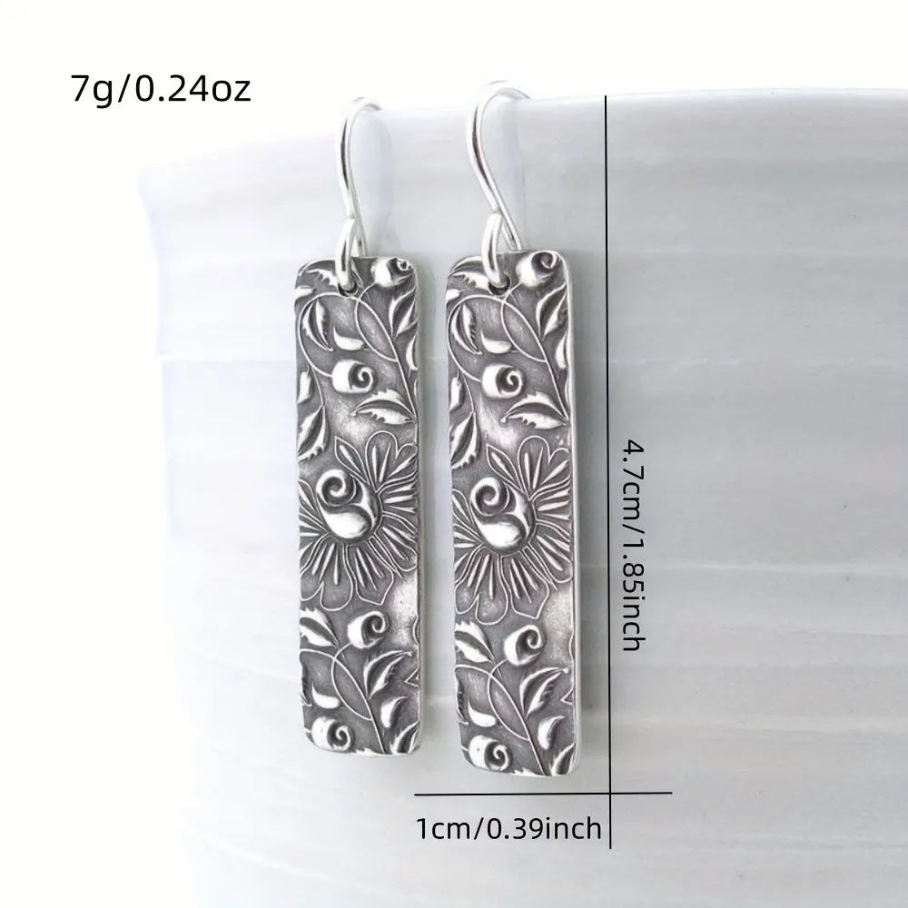 Silver-coloured long geometric drop earrings with carved vine patterns