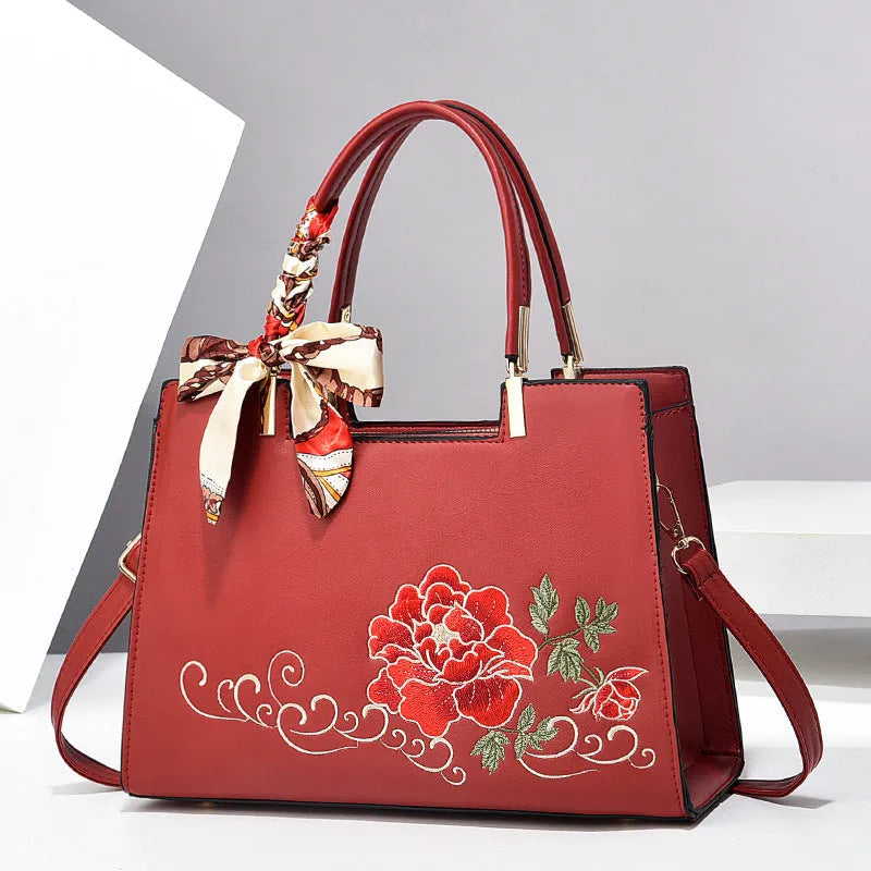 Large capacity embroidered women bag in PU, horizontal square shape, with zipper compartments and contrast colour detailing.