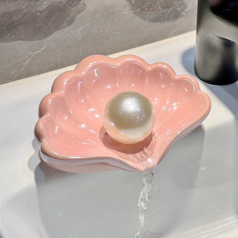 White shell-shaped plastic soap dish with drainage holes on a bathroom surface