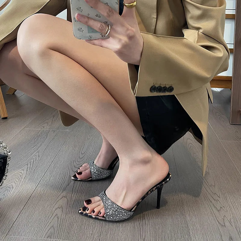 Black women's pointed-toe rhinestone sandals with a stiletto heel on a rubber sole.