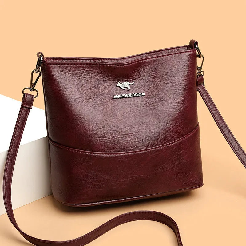 Women's PU leather crossbody bucket bag with wide strap, outer slit pocket, and internal phone and file pockets.