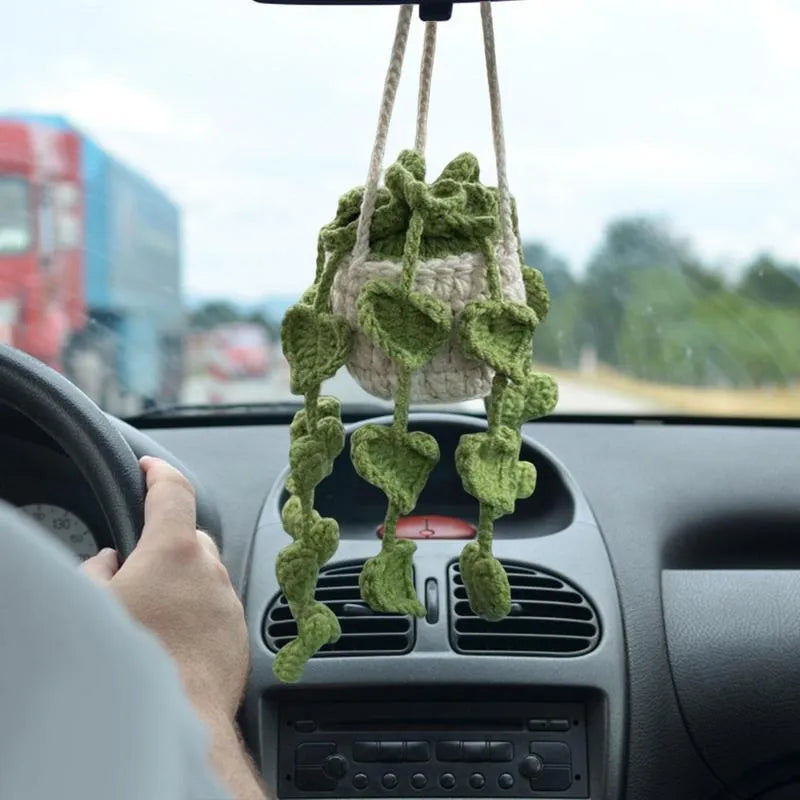 Green knitted wool car plant hanger with white rope, holding a small pot.