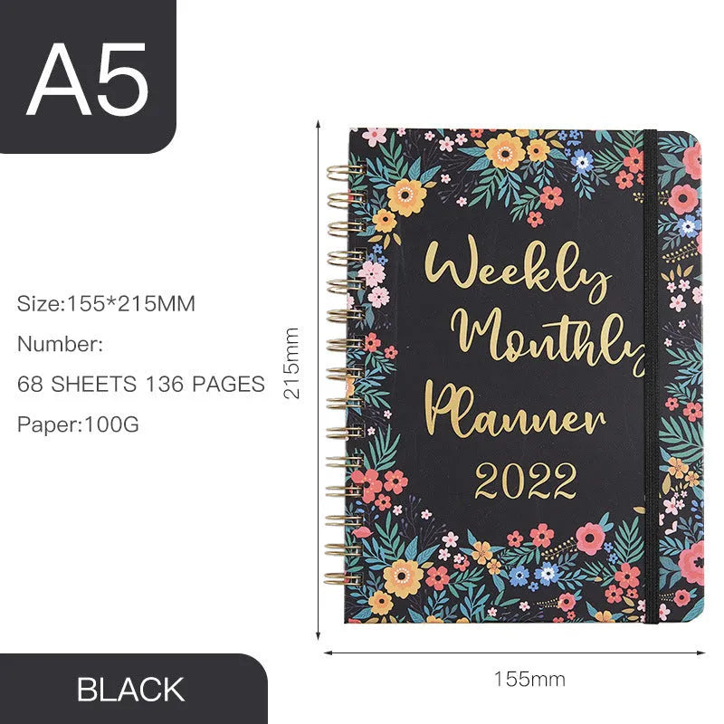 A5 spiral-bound notebook with a colourful floral design cover, lying open on a table.