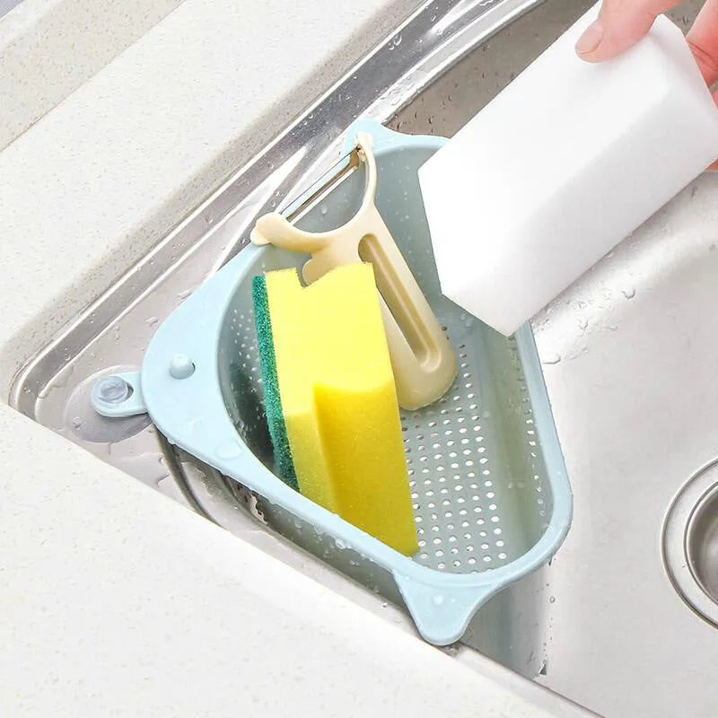 Triangular beige plastic kitchen sink storage rack with suction cup mount holding a sponge.