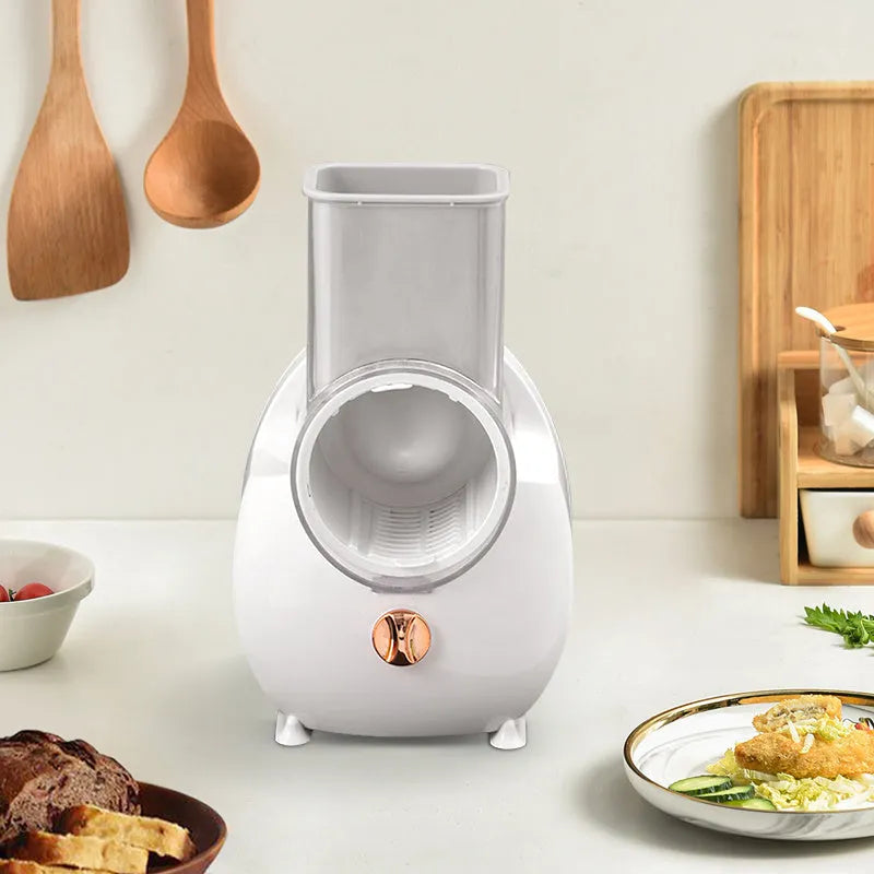 White electric vegetable slicer with rotary grater, feeding port, and multiple blade options on kitchen counter