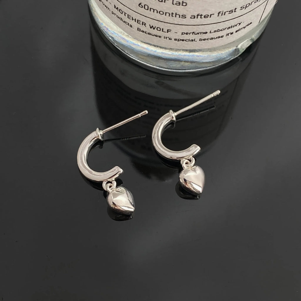 Gold copper C-shaped heart pendant earrings on white background