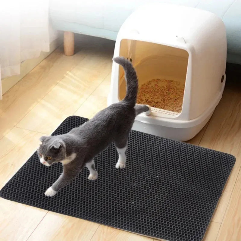Black waterproof EVA cat litter mat with honeycomb texture and quilted edge on a wooden floor