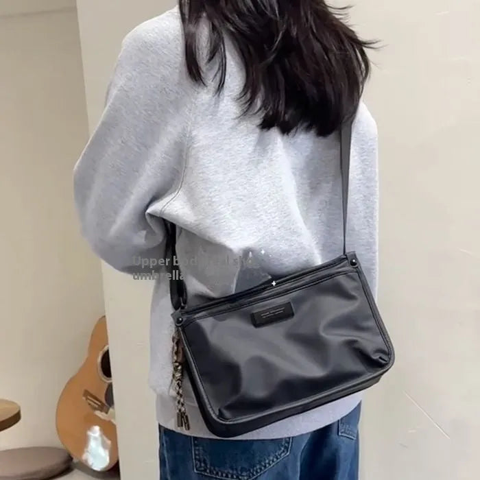 Small square crossbody bag in Oxford cloth, shown in a solid colour on an adjustable strap.