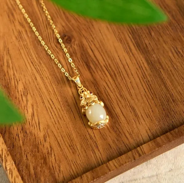 Cartoon character Hetian white jade antique gold pendant necklace with emerald pixiu charm on a chain.