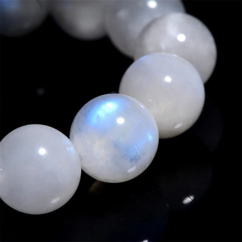 Natural blue moonlight round moonstone bead bracelet on a wrist, showing polished gemstone surface.
