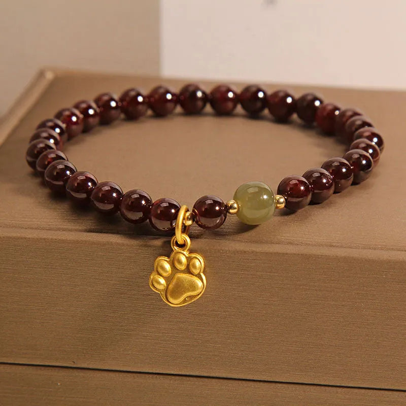 Women's crystal bracelet with a cat's paw garnet motif on a wrist.