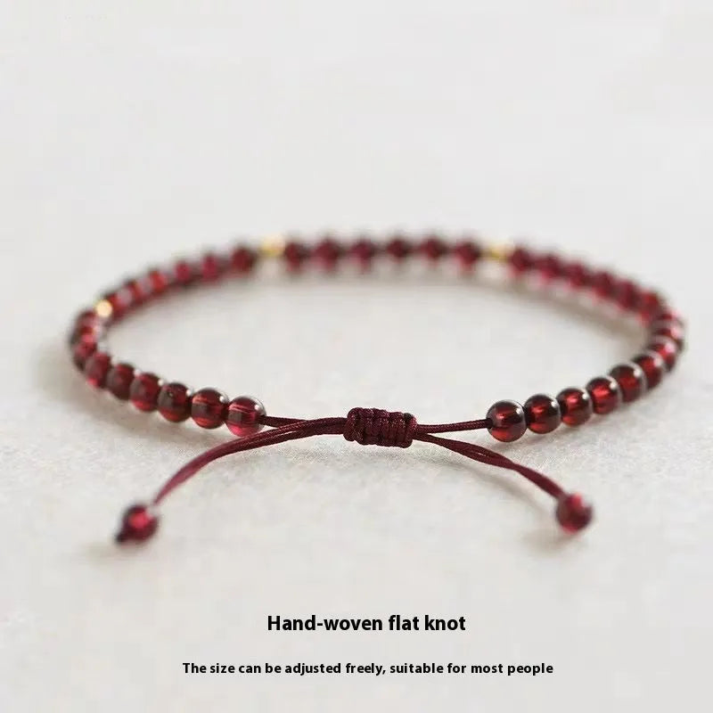 Hand-woven garnet bracelet with red rope and flexible wire construction showing national tide style
