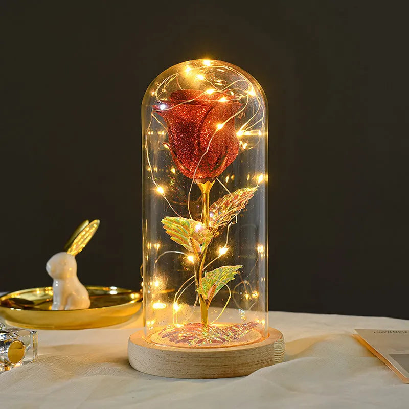 Glass dome covering a red eternal rose with coiled battery-powered LED lights on bendable copper wire.