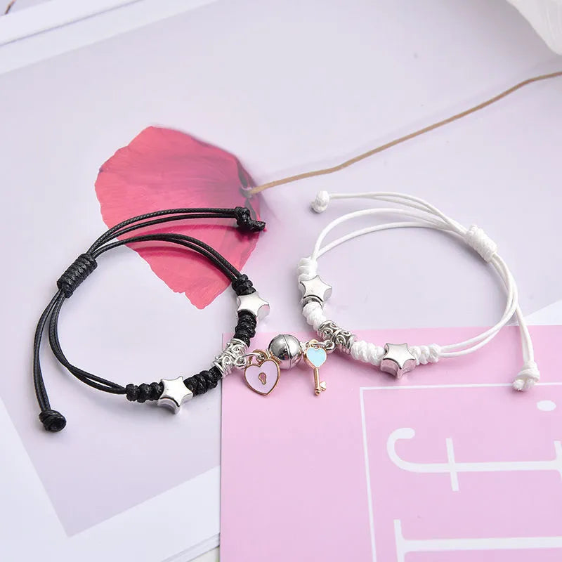 Pair of magnetic alloy bracelets with crown and heart charm designs on a wrist.