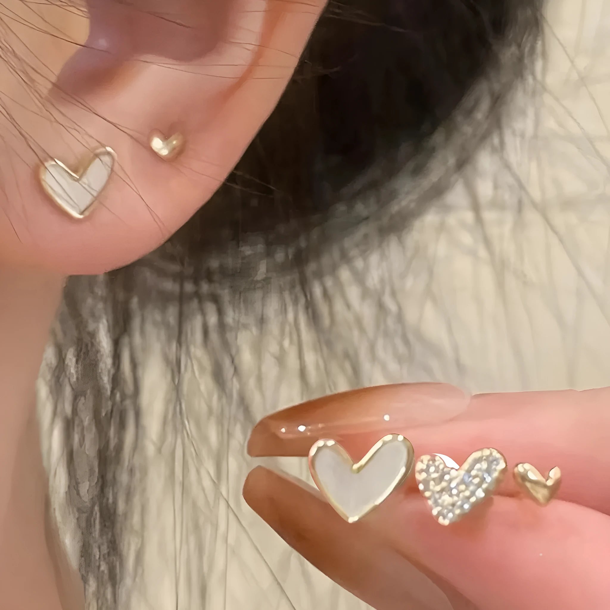Set of three pairs of women's heart-shaped alloy earrings in gold, black, black and white, and pink colours.