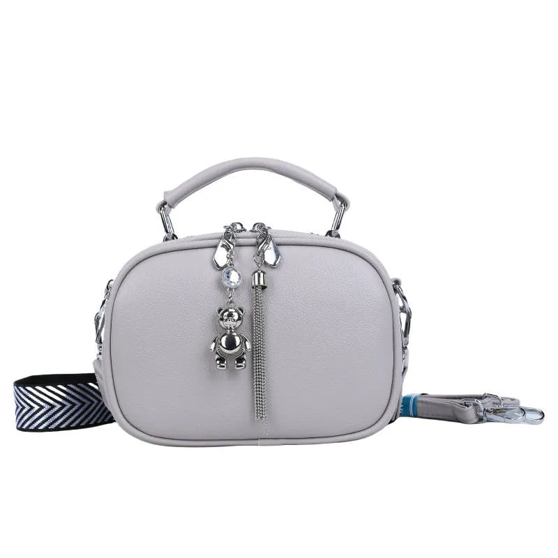 Women's small square stitching bag in oval shape with double shoulder strap showing internal mobile phone compartment.