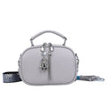 Women's small square stitching bag in oval shape with double shoulder strap showing internal mobile phone compartment.