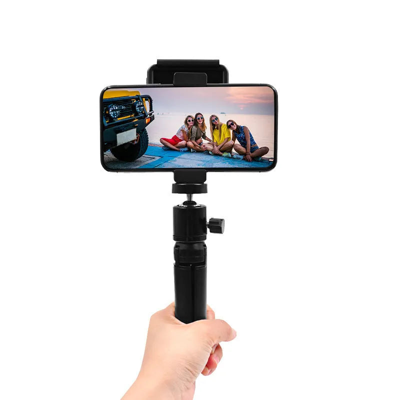 Silver aluminium smartphone bracket for tripod mounting next to a mobile phone.