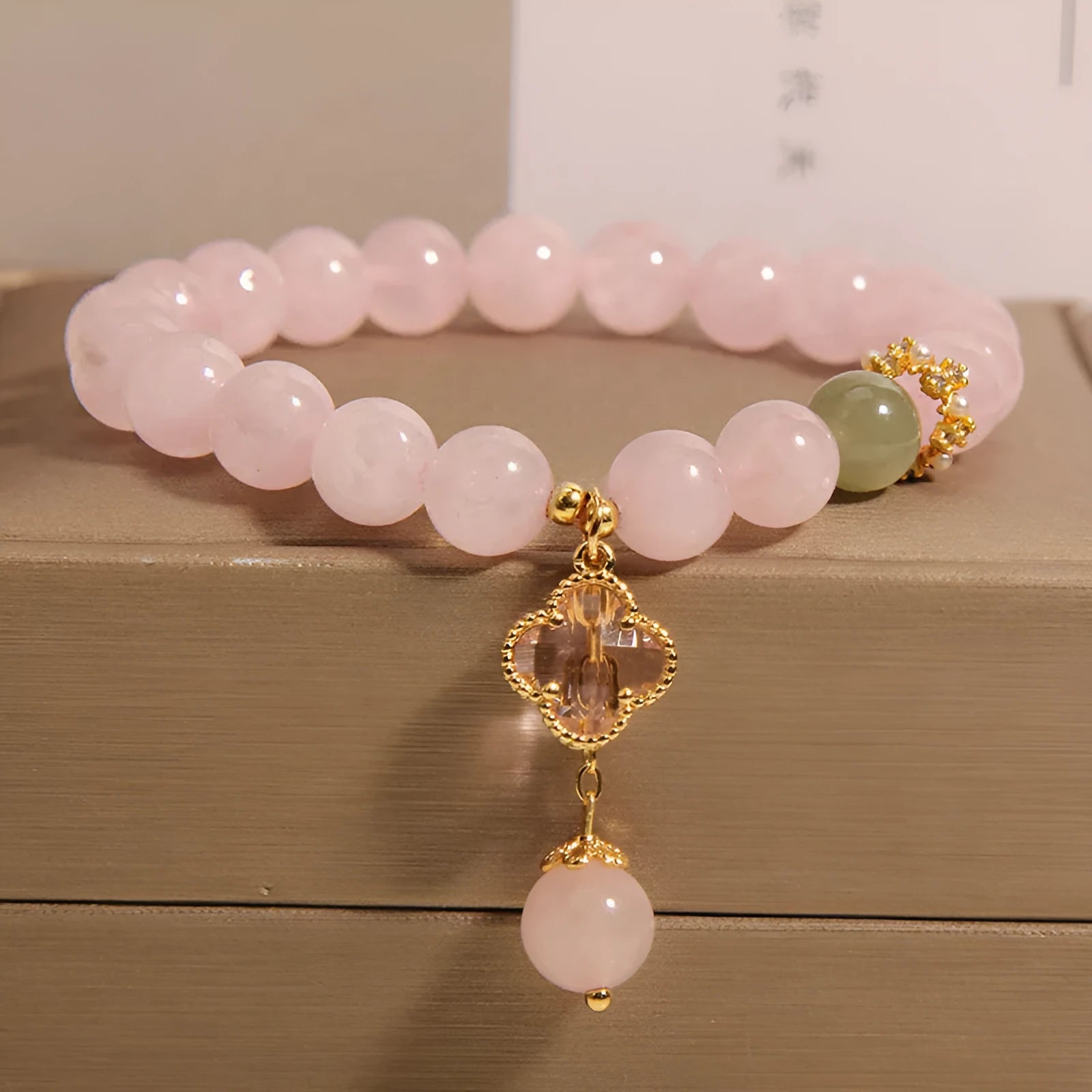 Pink crystal women's bracelet with a four-leaf clover pendant and sparkling rhinestone details.