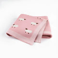 Grey and pink baby sheepskin blanket measuring 100cm by 80cm on a crib