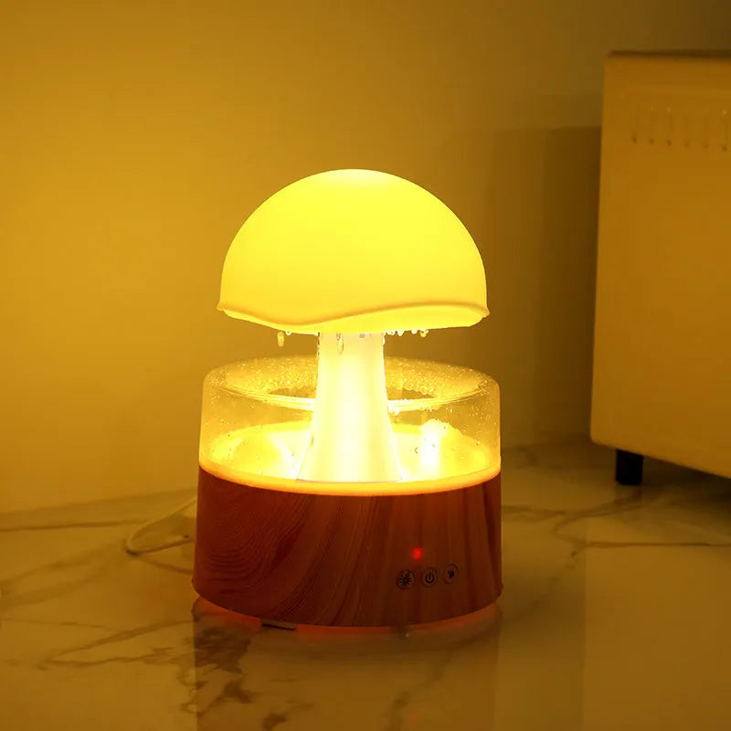 White cloud-shaped humidifier with simulated raindrops and colour-changing lights on wooden surface