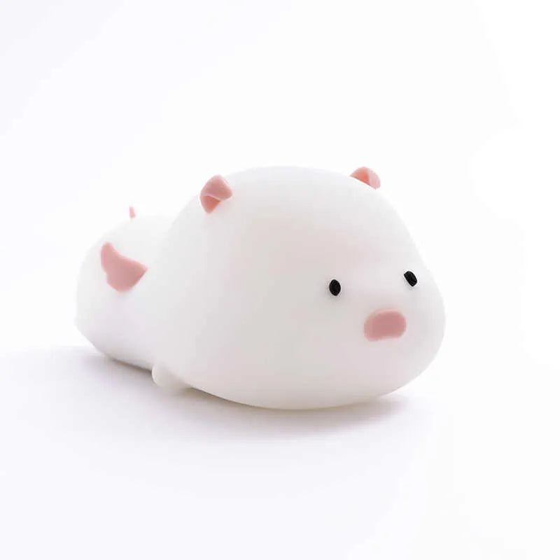 Blue rechargeable pig-shaped silicone night light with a sleeping design on a bedside table.
