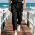 Men's light beige linen trousers with drawstring waist and straight-leg design laid flat