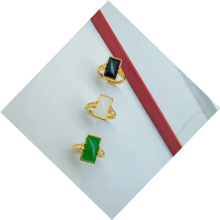 Adjustable brass gold-plated ring with a central green gemstone inlay on a finger.