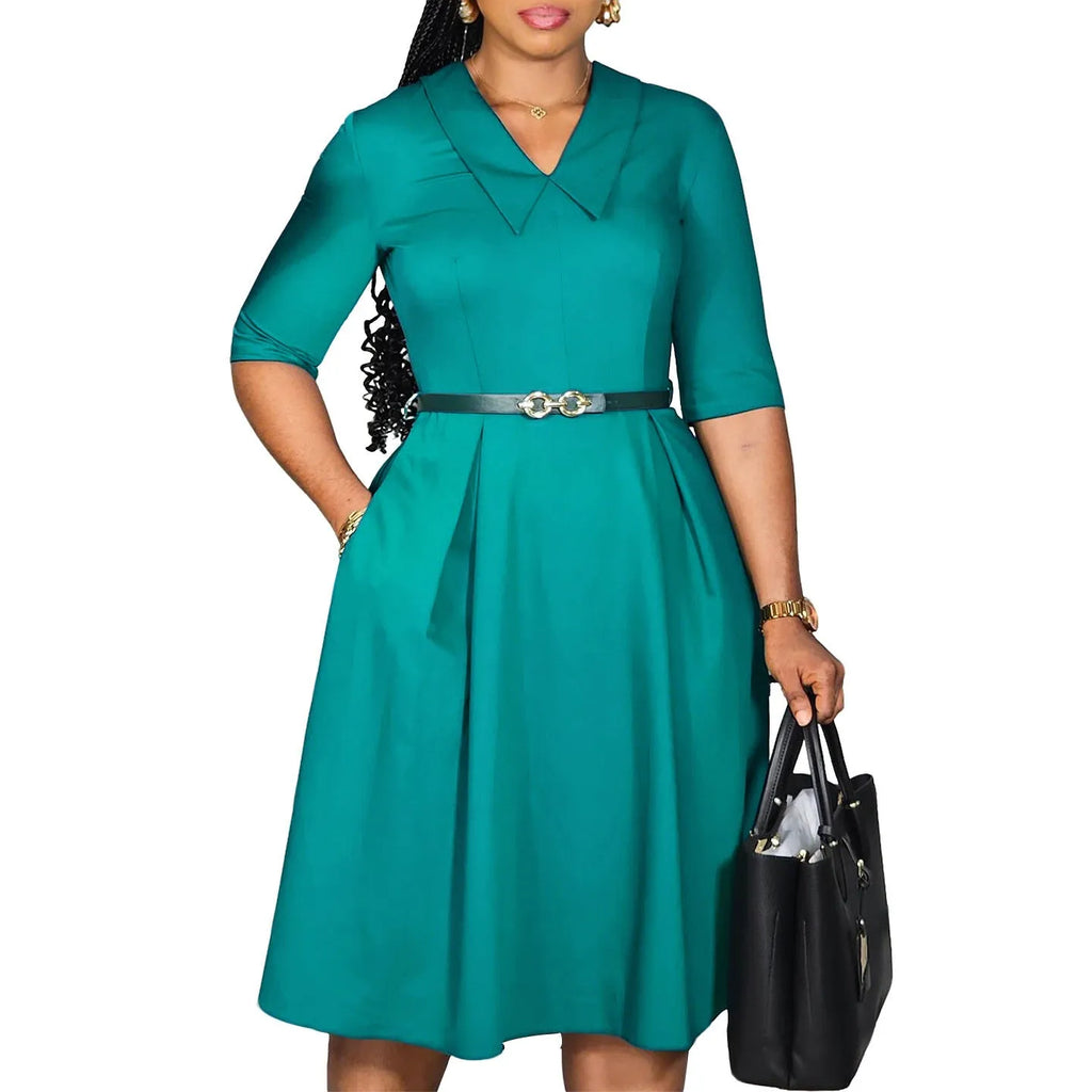 A woman wearing a solid colour African dress with half sleeves and a high waist, featuring a contrasting coloured belt.