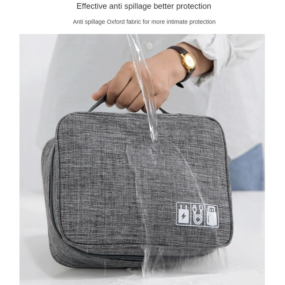 Black and grey waterproof travel cable organiser bag open, showing mesh pockets and removable padded dividers inside.
