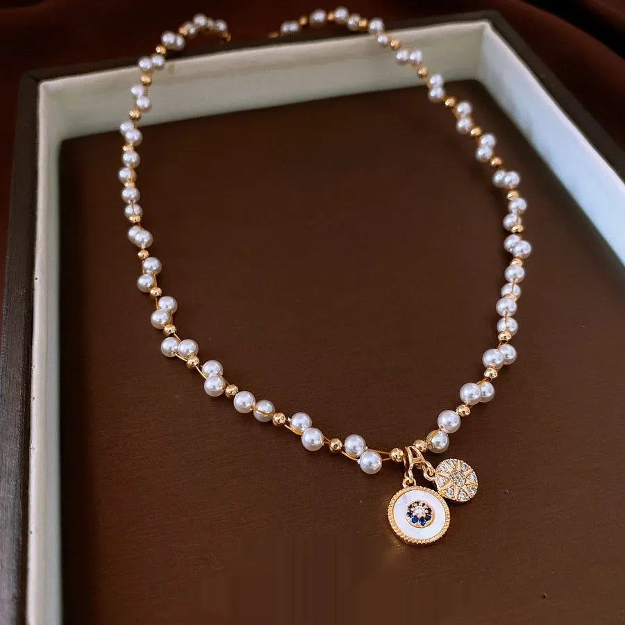 Gold and white electroplated necklace with round pearl pendant and zircon detailing on clavicle chain