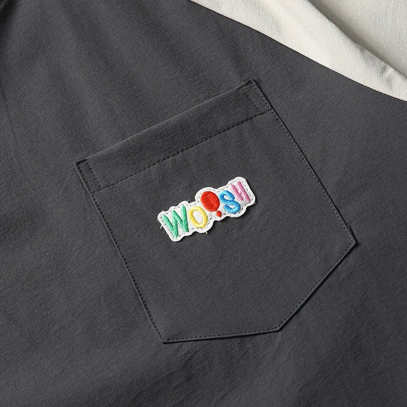 Dark grey loose fit t-shirt with light coloured raglan sleeves on a hanger