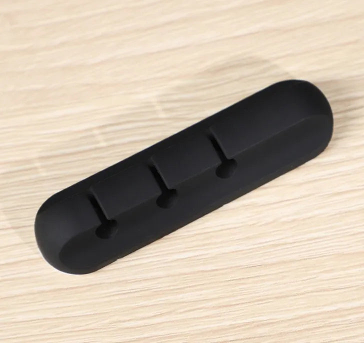 Black organic silicone desktop cable manager clips holding USB cables on a desk