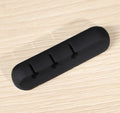 Black organic silicone desktop cable manager clips holding USB cables on a desk