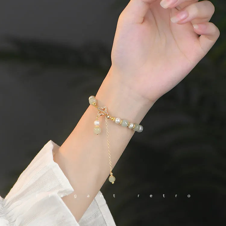 Women's bracelet with a round Hetian jade bead, pearl pendant, and gold-colour alloy clasp.