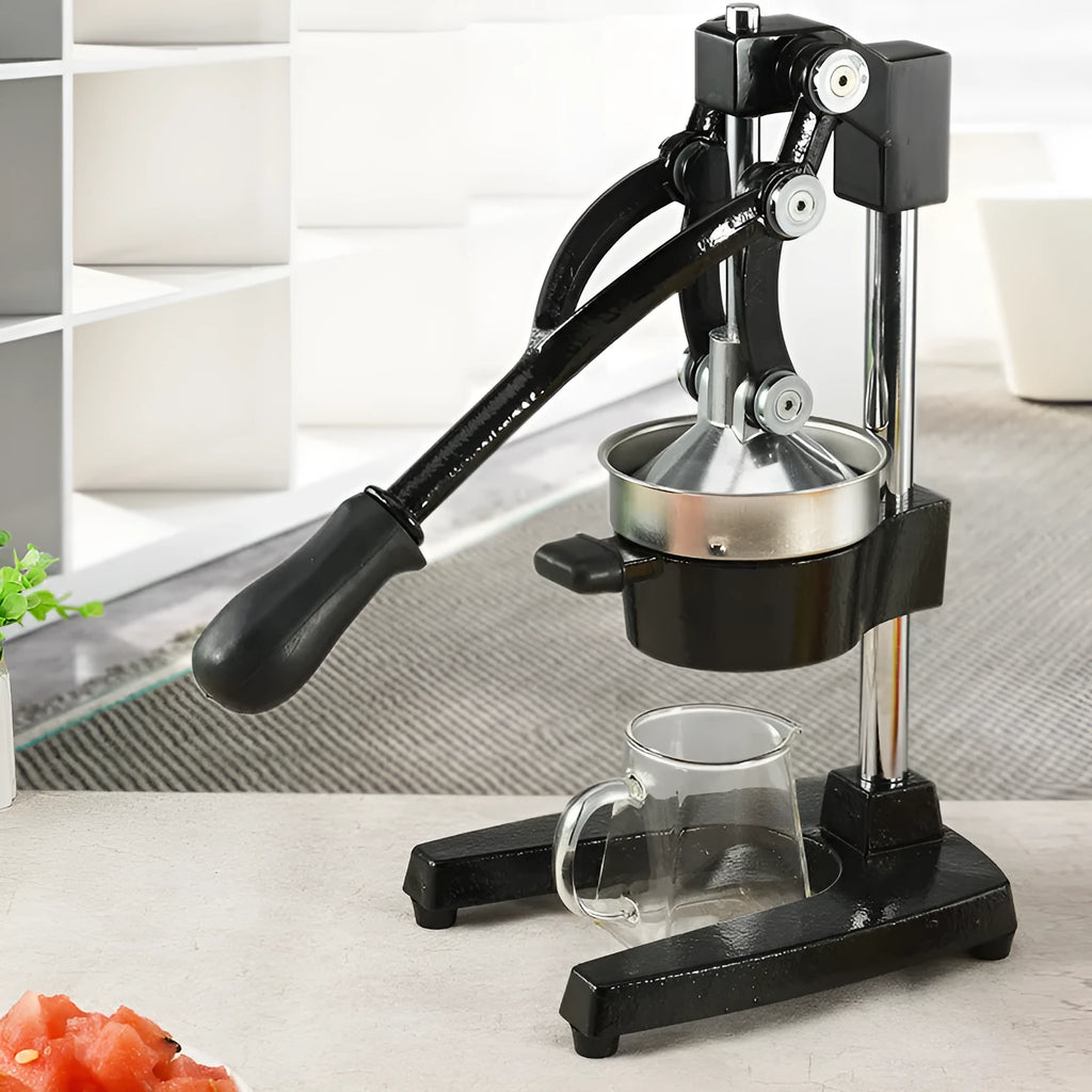 Tall black cast iron manual juicer with stainless steel cone on a kitchen counter