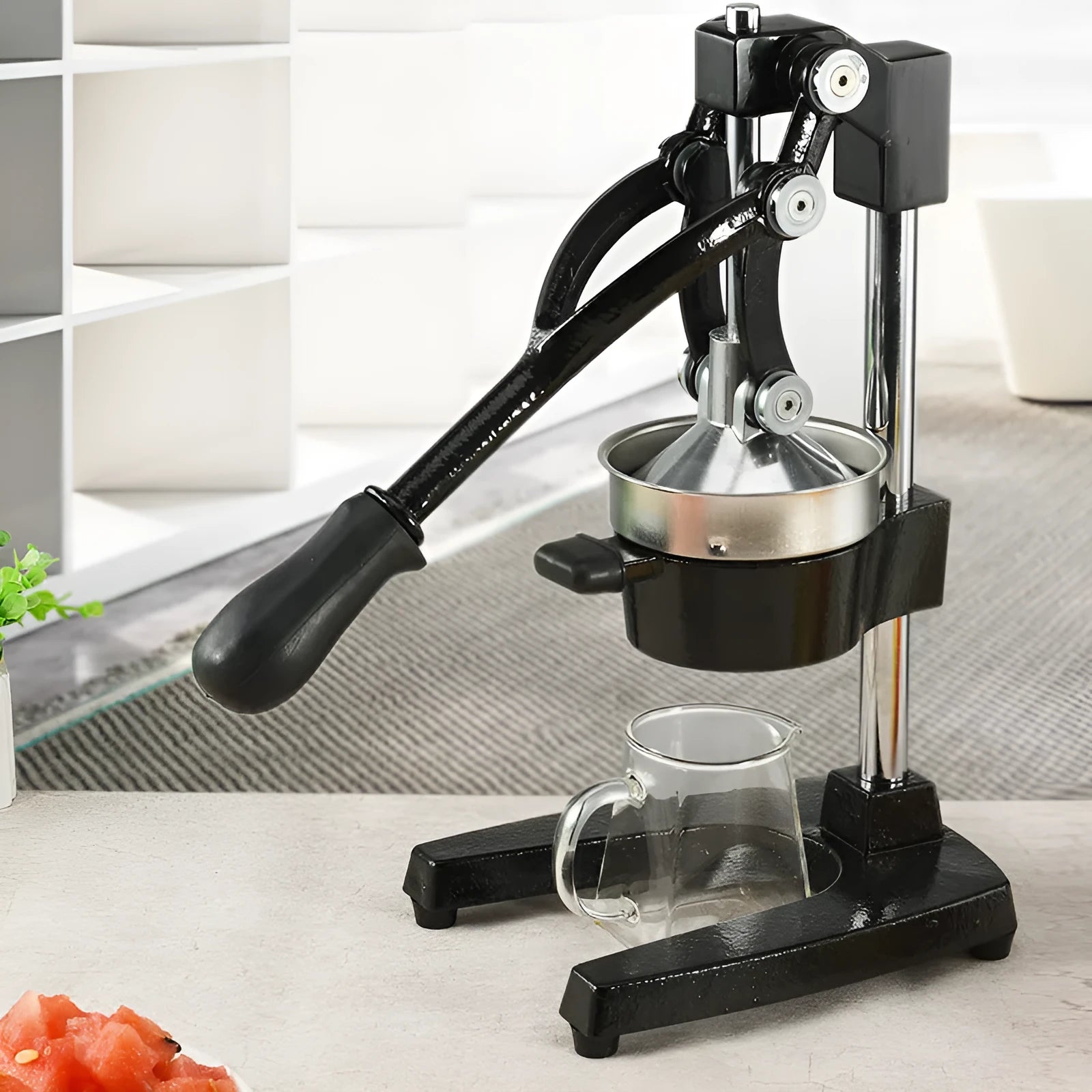 Tall black cast iron manual juicer with stainless steel cone on a kitchen counter