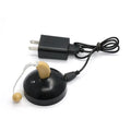 Black silicone rechargeable hearing aid amplifier with charging cable on a plain surface.