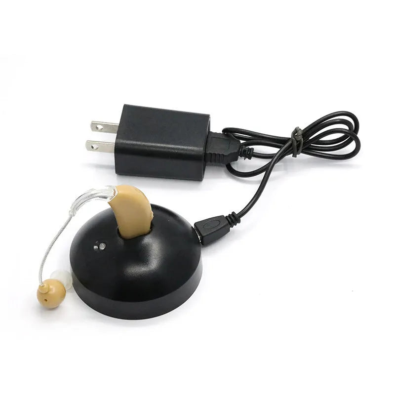 Black silicone rechargeable hearing aid amplifier with charging cable on a plain surface.