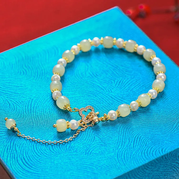 Women's bracelet with a round Hetian jade bead, pearl pendant, and gold-colour alloy clasp.